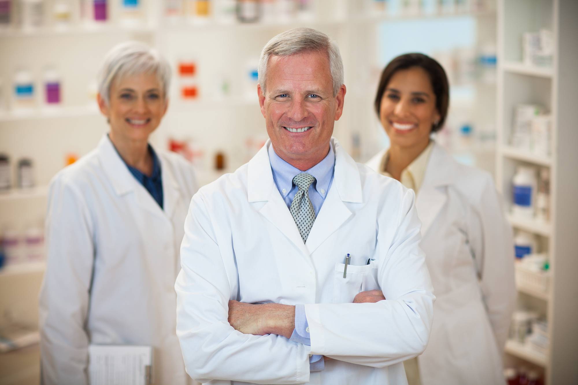 Three smiling pharmacists in a pharmacy